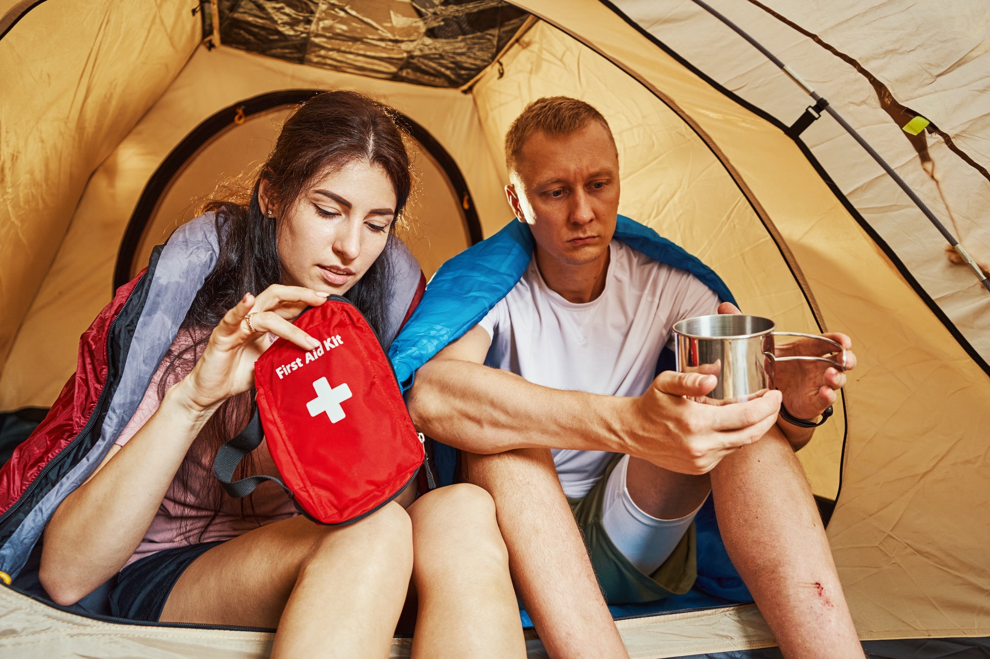 Young couple using first aid kit in tent